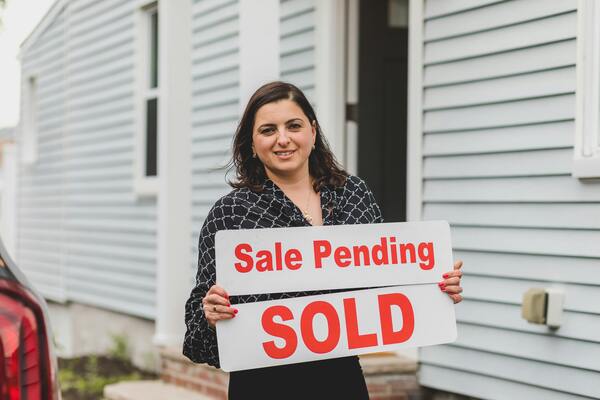 Woman with Sale Pending and Sold signs