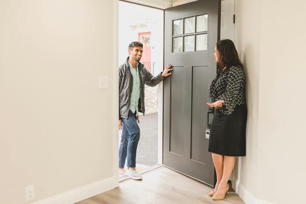 Agent welcoming client inside house